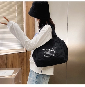 Detail of the high-capacity black canvas tote bag with white inspirational text printing