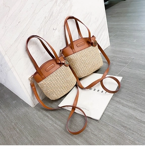 Detail of straw woven bucket bag with brown leather trim and detachable shoulder strap
