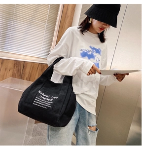Detail showing high-capacity black canvas tote bag with white minimalist typography