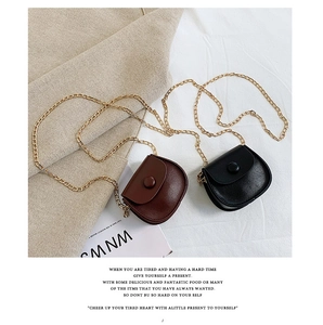 Detail of mini saddle bags in black and brown leather with golden metal chain straps