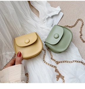 Detail of mini saddle cross-body bags in yellow and green with gold chain straps