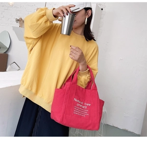 Detail view of red canvas tote bag with white text print and sturdy dual handles