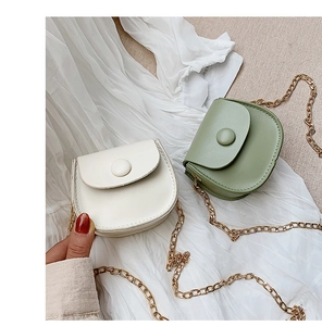 Detail view of mini round saddle bags in beige and green colors with gold chain straps