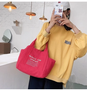 Red canvas tote bag with side pockets and quote shown in a casual lifestyle setting