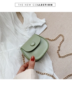 Detail of a light green semi-circular mini bag featuring a gold chain and matte texture