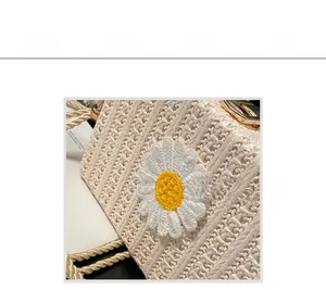 Détail d'un sac en paille tressée avec broderie marguerite blanche et chaîne dorée