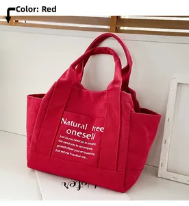 Detailed view of the red canvas tote bag with thick handles and side storage pocket