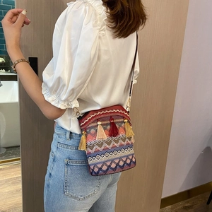 Borsa a secchiello tessuta in stile etnico con nappe colorate e tracolla indossata da modella