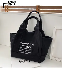 Close-up of black canvas tote bag with white text on a minimal interior background