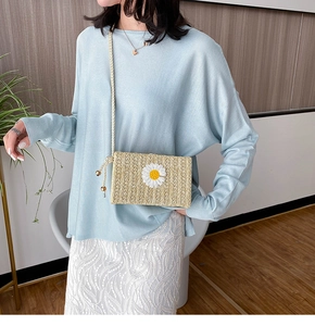 Détail du sac bandoulière en paille avec broderie marguerite et bandoulière perlée dorée