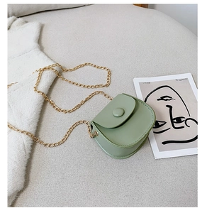 Detail view of a mint green saddle-shaped kid's crossbody bag with gold chain strap