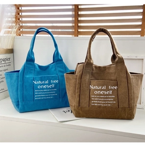Close-up of blue and brown canvas tote bags with front pockets and elegant white typography