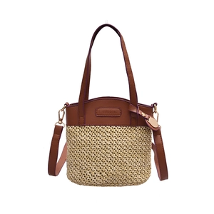 Woven straw bucket bag with brown leather handles and adjustable shoulder strap