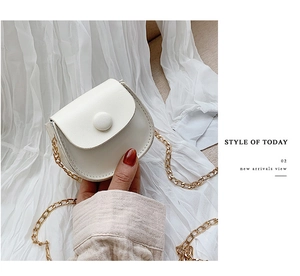 Detail of a mini white leather saddle bag for girls with gold chain strap and round buckle