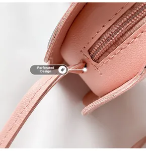 Detail view of pink leather bag with perforated shoulder strap design and zipper closure