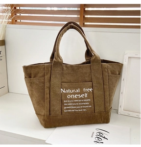 Detailed texture of brown canvas tote bag featuring front pocket and white script design