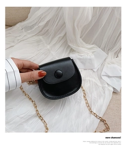 Close-up of black mini saddle bag featuring smooth PU leather and gold chain strap