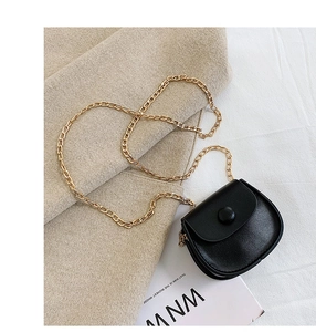 Close-up of black leather mini saddle bag with golden chain strap and magnetic clasp