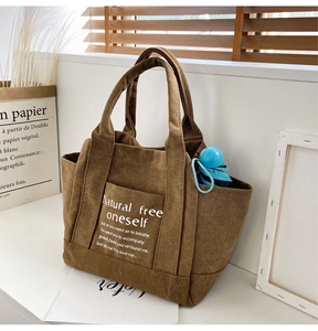 Detailed view of a brown canvas tote bag featuring front pocket and spacious interior