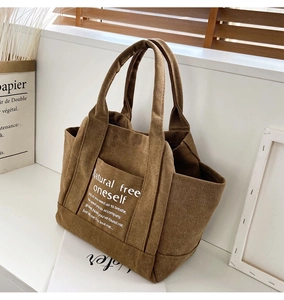 Detailed texture of brown canvas tote bag with front pocket and white printed text