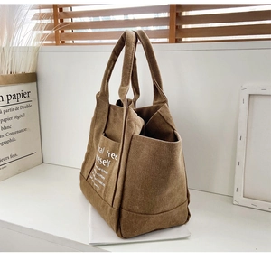 Detailed side view of multi-pocket corduroy tote bag in brown with textured cord fabric