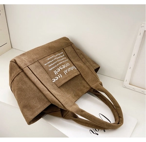 Brown canvas tote bag detail featuring white 'Natural free oneself' text print and wide strap