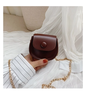 Detailed close-up of dark brown mini crossbody bag with a gold chain strap and round buckle