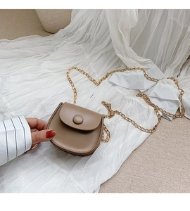 Detailed macro of a brown mini saddle bag with gold chain strap and magnetic buckle