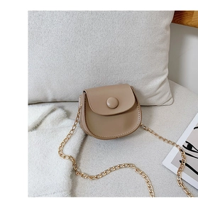 Detail view of stylish beige saddle bag with gold chain strap and snap button closure