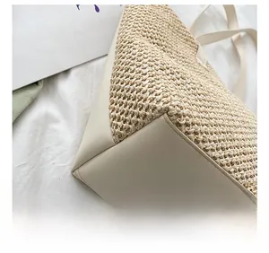 Detail shot of woven straw tote bag featuring a reinforced wear-resistant faux leather base