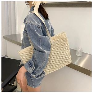 Detail of minimalist beige woven straw tote bag texture and long shoulder straps