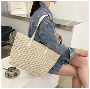 Detail of cross-woven texture and leather strap on beige woven tote bag for summer