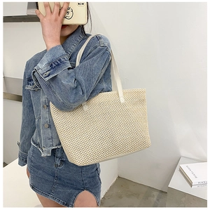 Detail view of large straw tote bag with white faux leather straps on female model