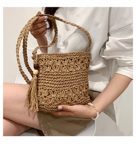 Detail of hand-woven straw bag with floral pattern, tassels, and wooden beads