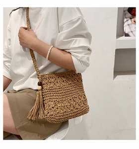 Detailed view of handmade woven straw crossbody bag with tassels and wooden beads
