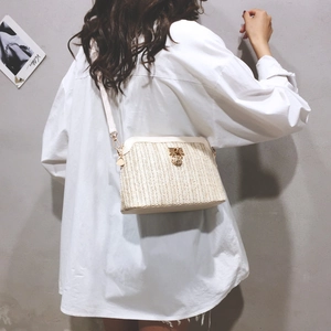 Detail van crème geweven crossbodytas met gouden draaisluiting en visgraattextuur