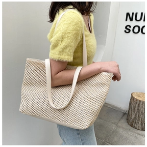 Detailed view of cream woven tote bag with premium leather straps on female model