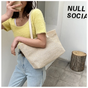 Detailed view of woven straw tote bag texture with off-white leather strap and base