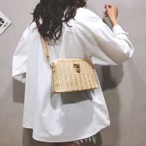 Detail van schelpvormige geweven crossbodytas met lederen klep en metalen sluiting
