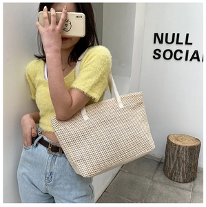 Detail of hand-woven beige straw tote bag with premium leather shoulder straps