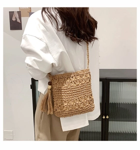Detail of hand-woven straw bag featuring hollow floral pattern and wooden bead tassel