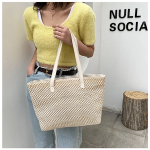 Detailed close-up of a large linen tote bag with cream leather straps on a model