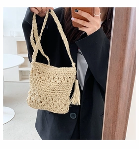 Detail shot of handwoven straw crossbody bag with tassels and hollow pattern design