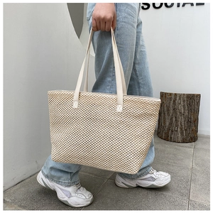 Detail of woven straw tote bag with cream leather handles and textured fiber stitching
