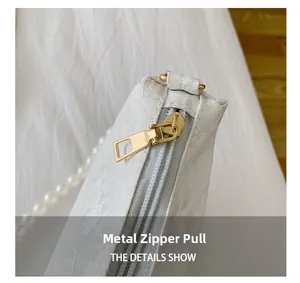 Detail show of golden hardware zipper pull on white lace pleated baguette bag