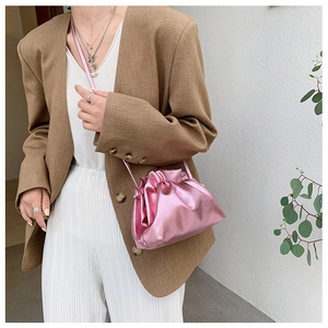 Détail du sac nuage plissé rose métallisé porté avec un blazer de ton terreux