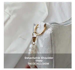 Detail of white lace handbag featuring detachable faux pearl strap and gold hardware
