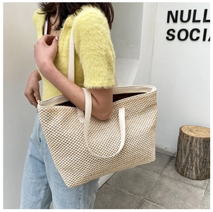 Detail of hand-woven straw tote bag with cream faux leather straps and fine texture