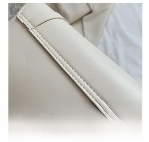 Detail shot of precise machine stitching on cream-colored leather handbag edge