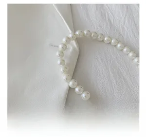 Close-up of glossy white pearl handle chain detail on elegant women's handbag